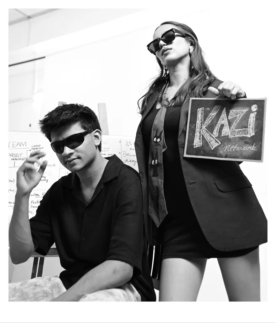 Two Kazi team members holding a hand-lettered Kazi Network sign