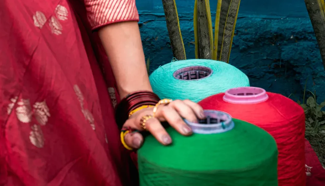 Orient Yarn — hand resting on colourful yarn cones