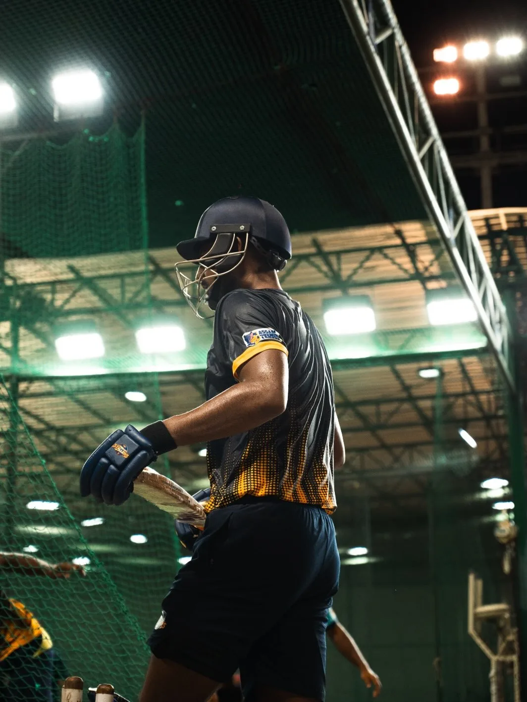 Batter shouldering the bat inside the floodlit nets