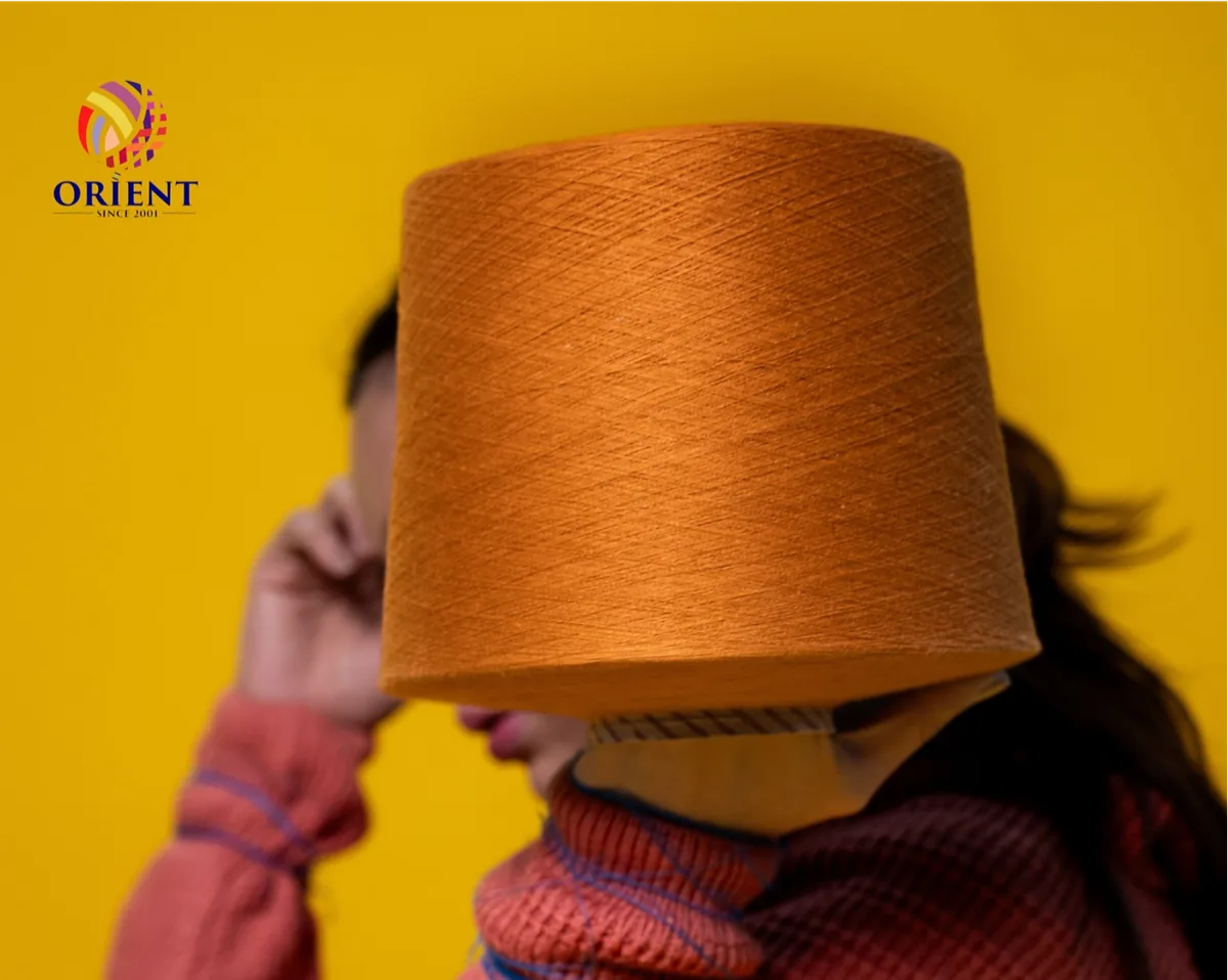 Orange yarn cone balanced on a head, yellow backdrop