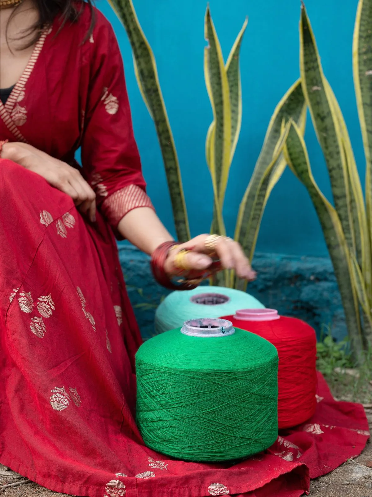 Woman in a red saree arranging yarn cones