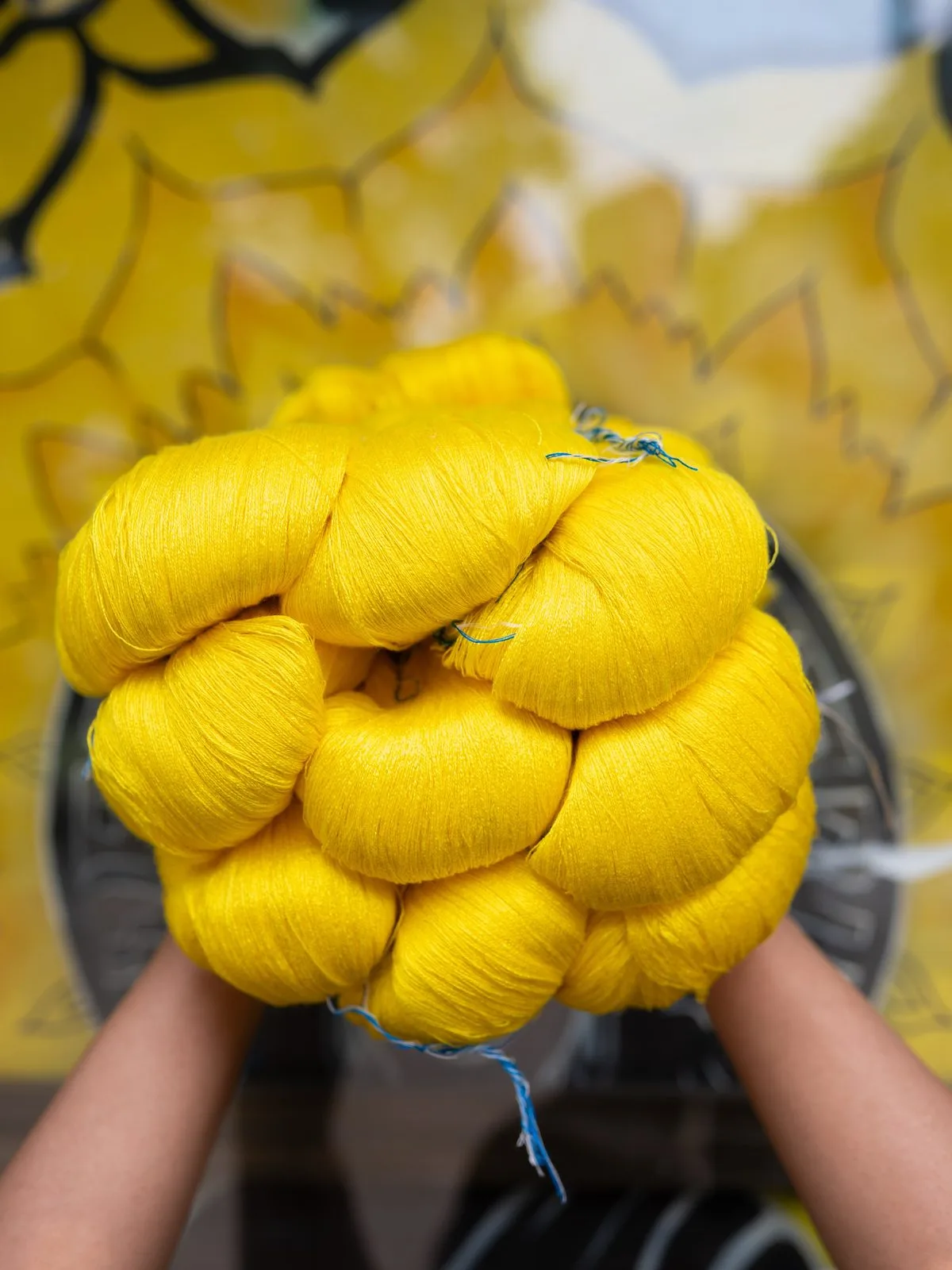 Hands holding a bundle of yellow yarn
