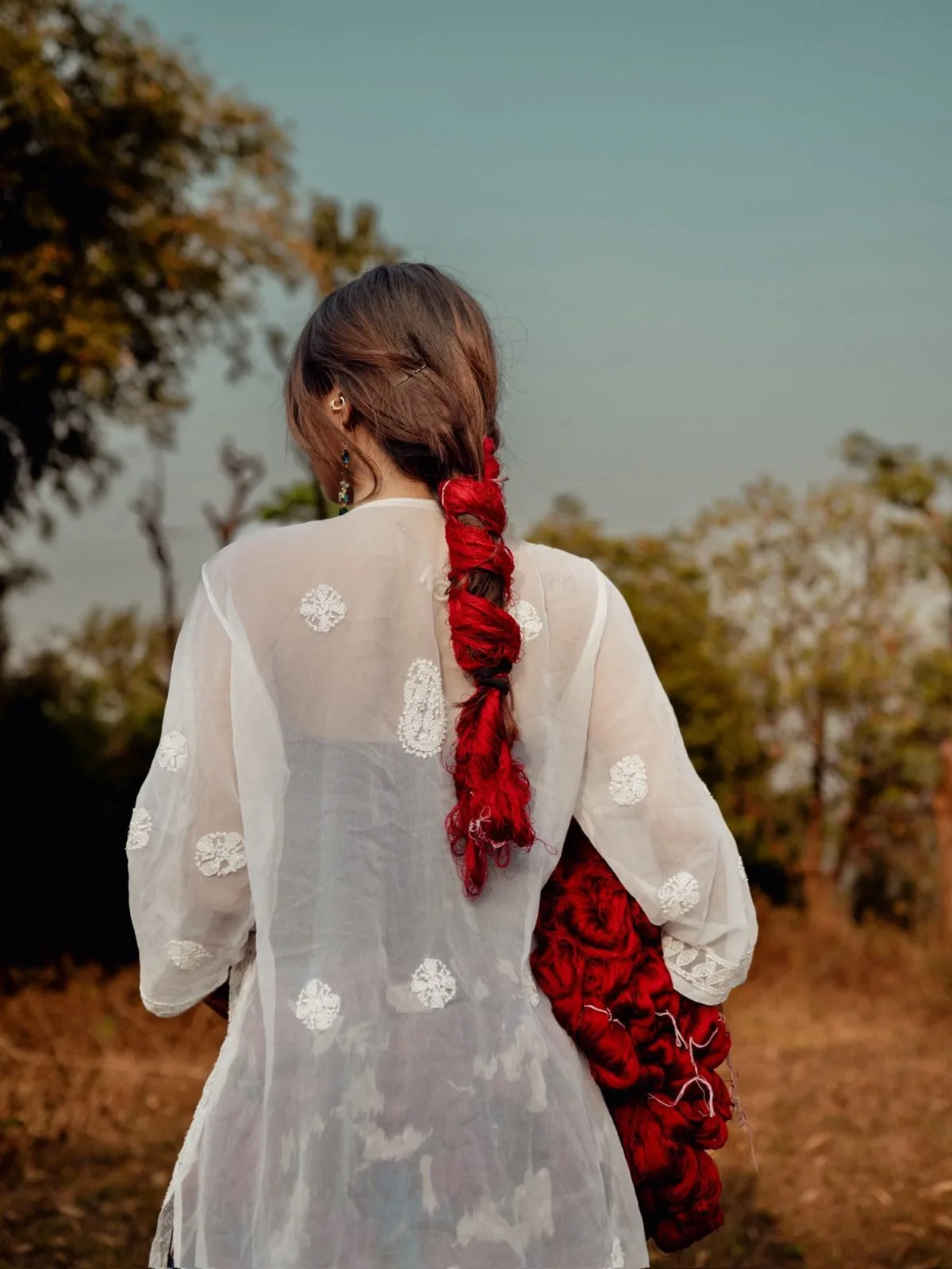 Woman in a white dress with a red braided ribbon