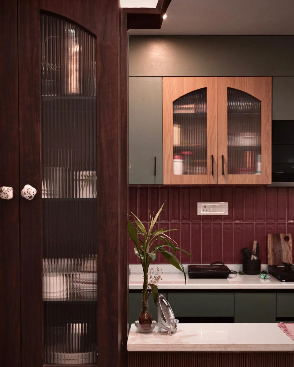 Fluted-glass wooden cabinet with a bamboo plant, seen past a dark timber partition