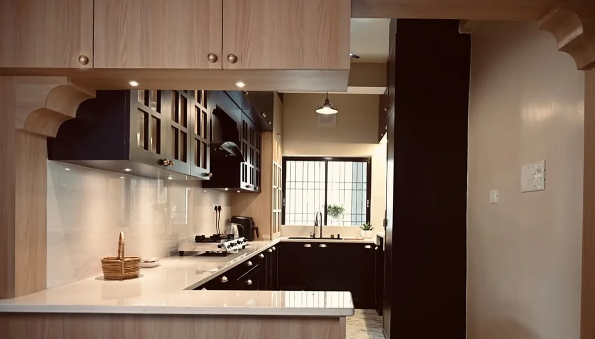 Pale wood and black galley kitchen lit from a rear window
